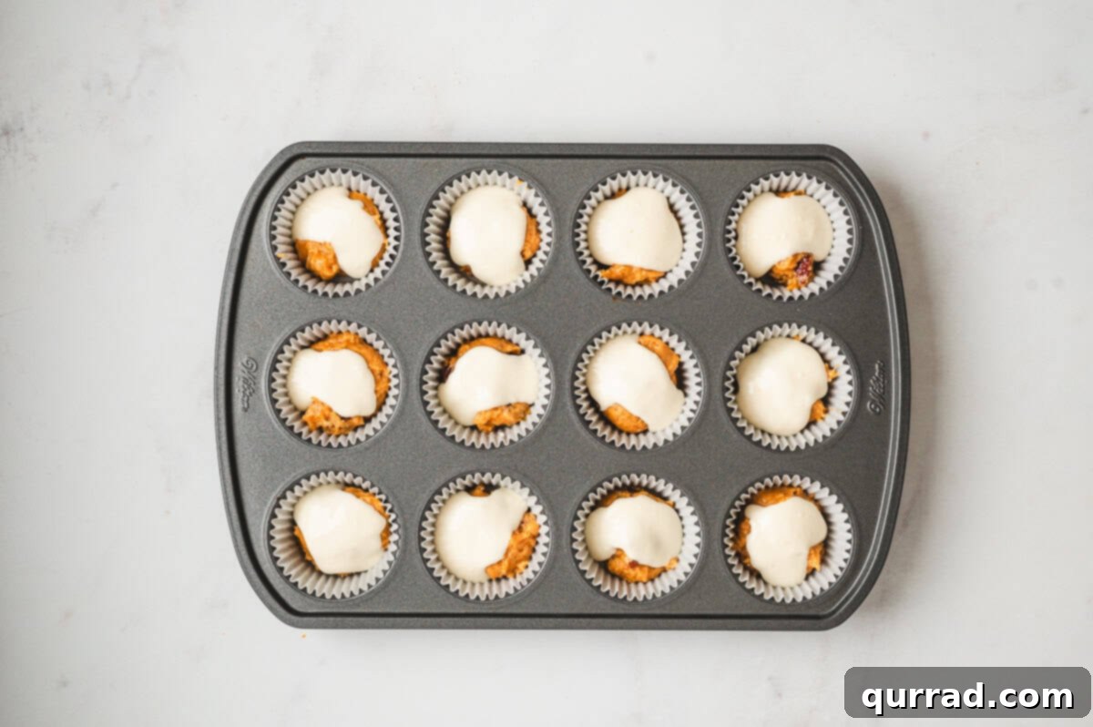 Pumpkin Cream Cheese Swirl Muffins 9 Muffin pan with dollops of cream cheese filling placed on top of the first layer of pumpkin batter.