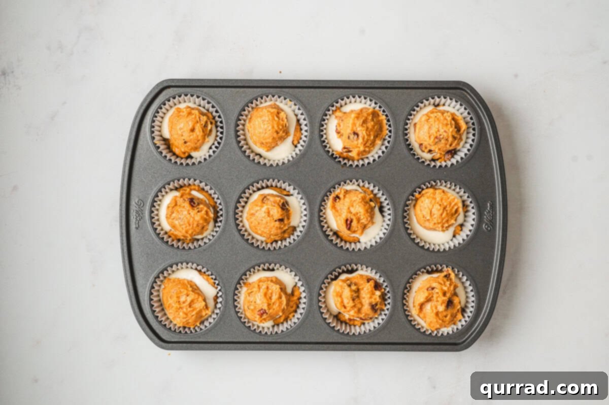 Pumpkin Cream Cheese Swirl Muffins 10 Muffin tin showing the cream cheese filling covered with the final layer of pumpkin muffin batter.