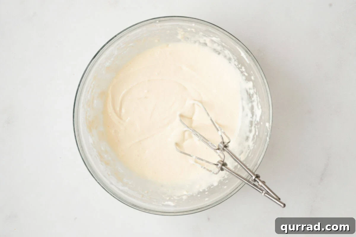 Pumpkin Cream Cheese Swirl Muffins 5 A glass bowl filled with smooth cream cheese filling and electric mixer beaters resting inside.