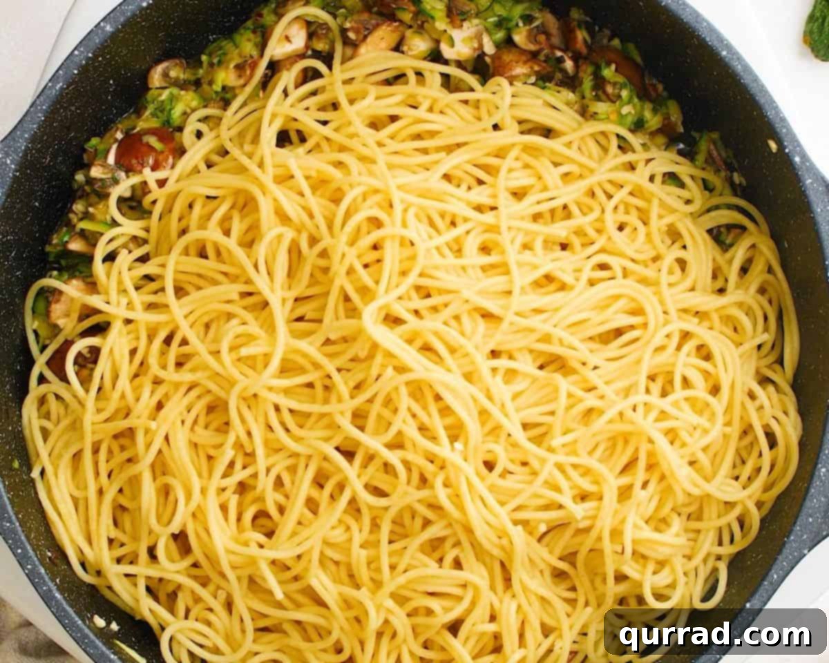 Savory Zucchini Mushroom Pasta 6 Adding the freshly cooked spaghetti directly into the pan with the sautéed zucchini and mushroom mixture.
