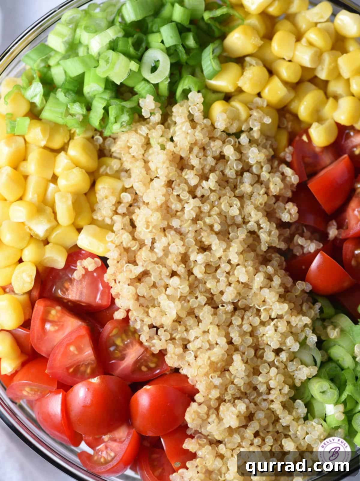Vibrant Quinoa Medley 3 A bowl filled with uncooked quinoa, fresh corn kernels, halved cherry tomatoes, and diced scallions, ready for preparation.