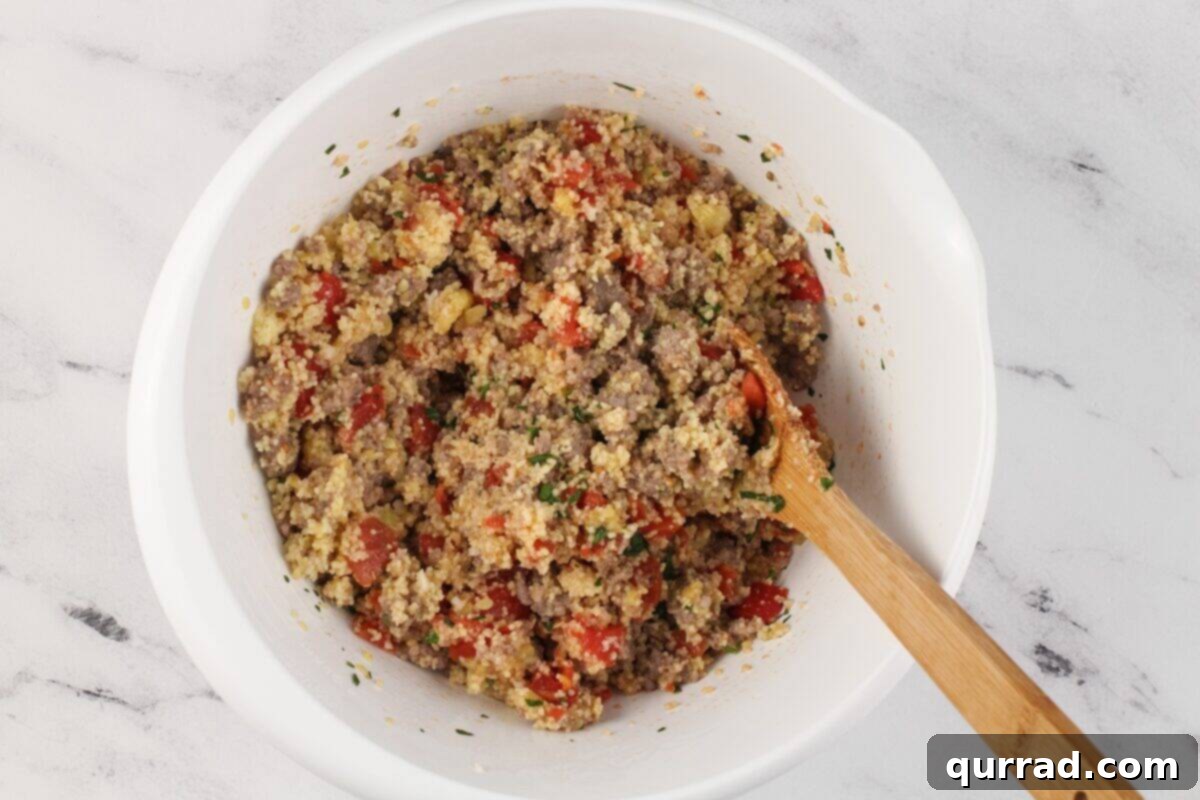 Hearty Italian Zucchini Boats 10 A large white bowl containing the combined sausage mixture, couscous, and diced tomatoes for the zucchini filling.