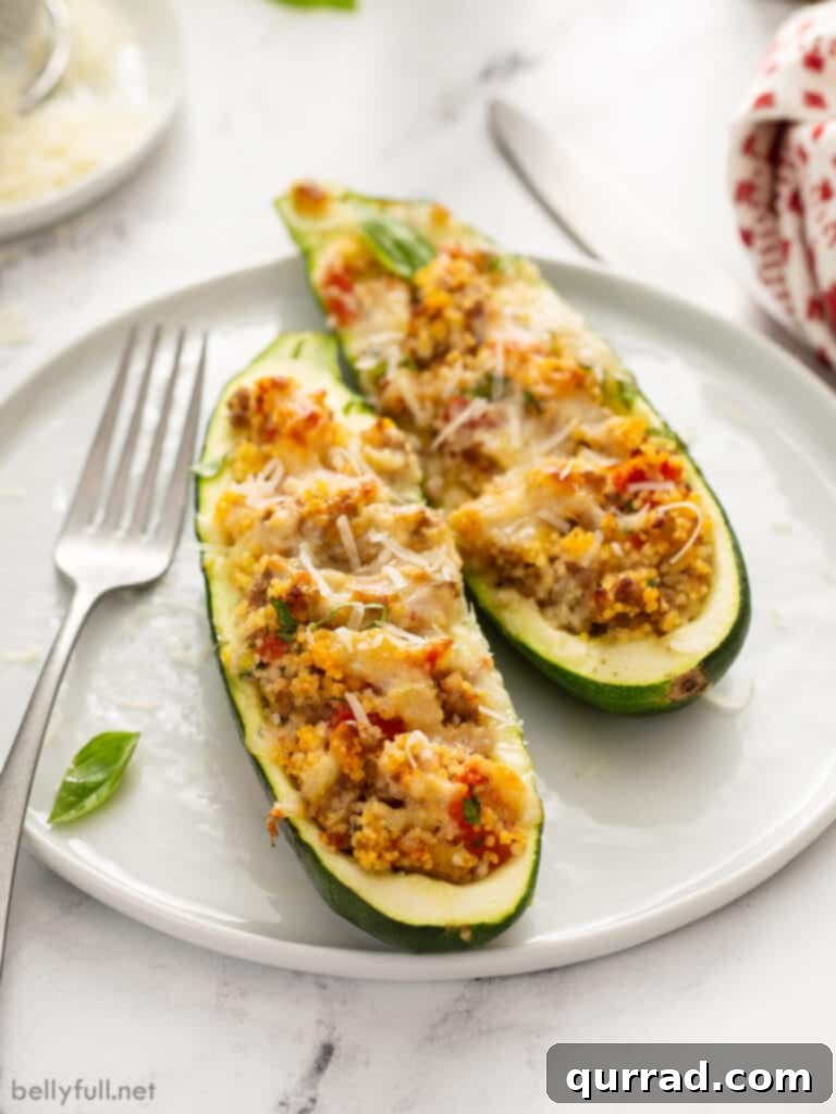 Hearty Italian Zucchini Boats 12 Two perfectly baked Italian sausage stuffed zucchini halves on a white plate, garnished with fresh herbs.
