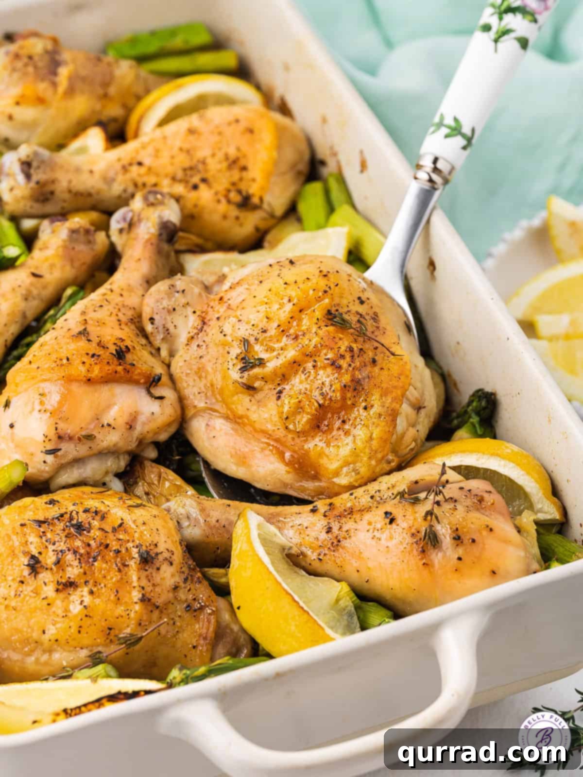 Effortless One-Pan Chicken Meal 4 Serving spoon lifting a perfectly roasted chicken thigh with crispy skin, alongside tender vegetables, from the pan.