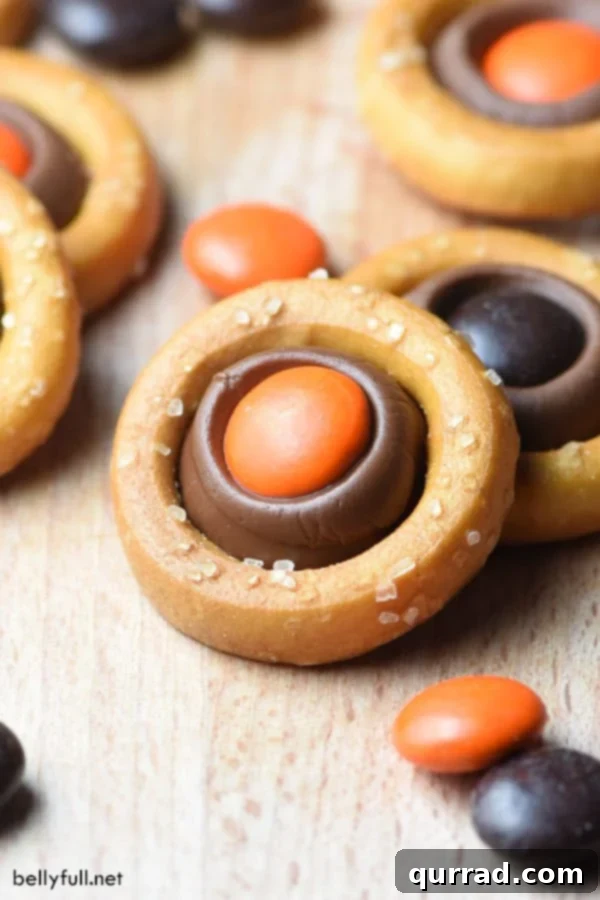 Monster Pretzel Rings 2 A close-up of a Halloween Pretzel Ring with a melted Hershey's kiss and an orange M&M, showcasing its sweet and salty appeal