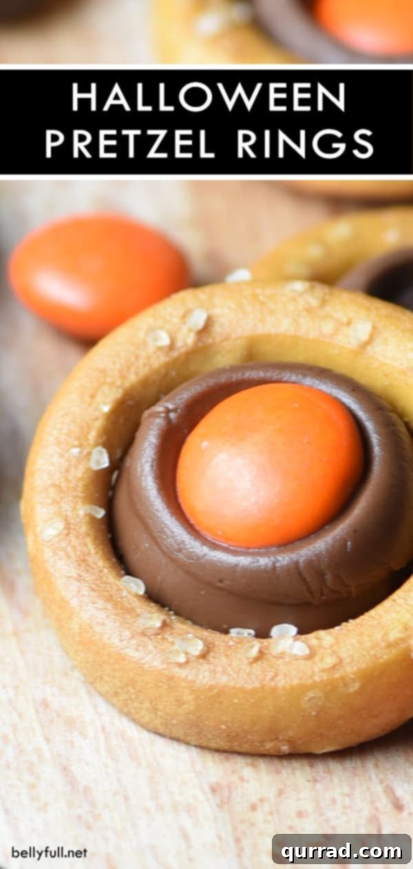 Easy Halloween Pretzel Rings: Perfect Party Treat A vibrant Halloween Pretzel Ring with melted chocolate and a single M&M, photographed on a dark surface to highlight its festive and appealing colors