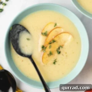 Bowl of parsnip soup with apple slices and thyme sprigs