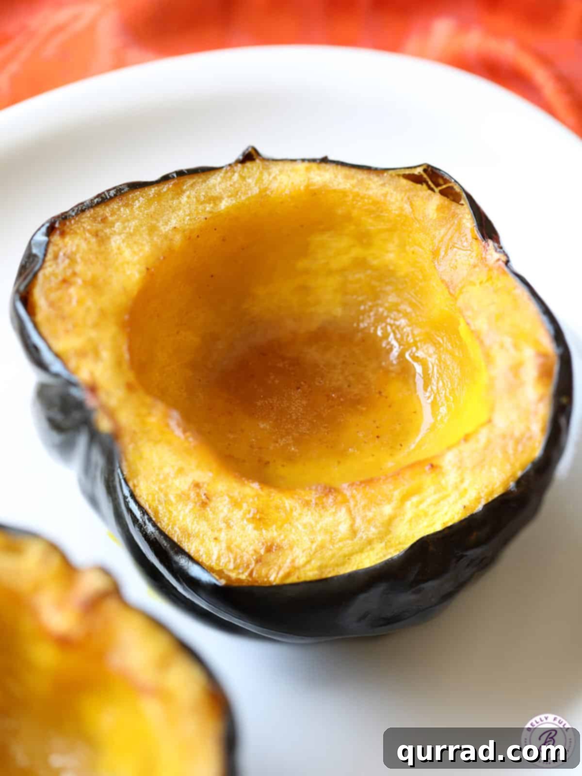 Half of a perfectly roasted acorn squash, glistening with melted butter and brown sugar, ready to be served as a delightful side dish.