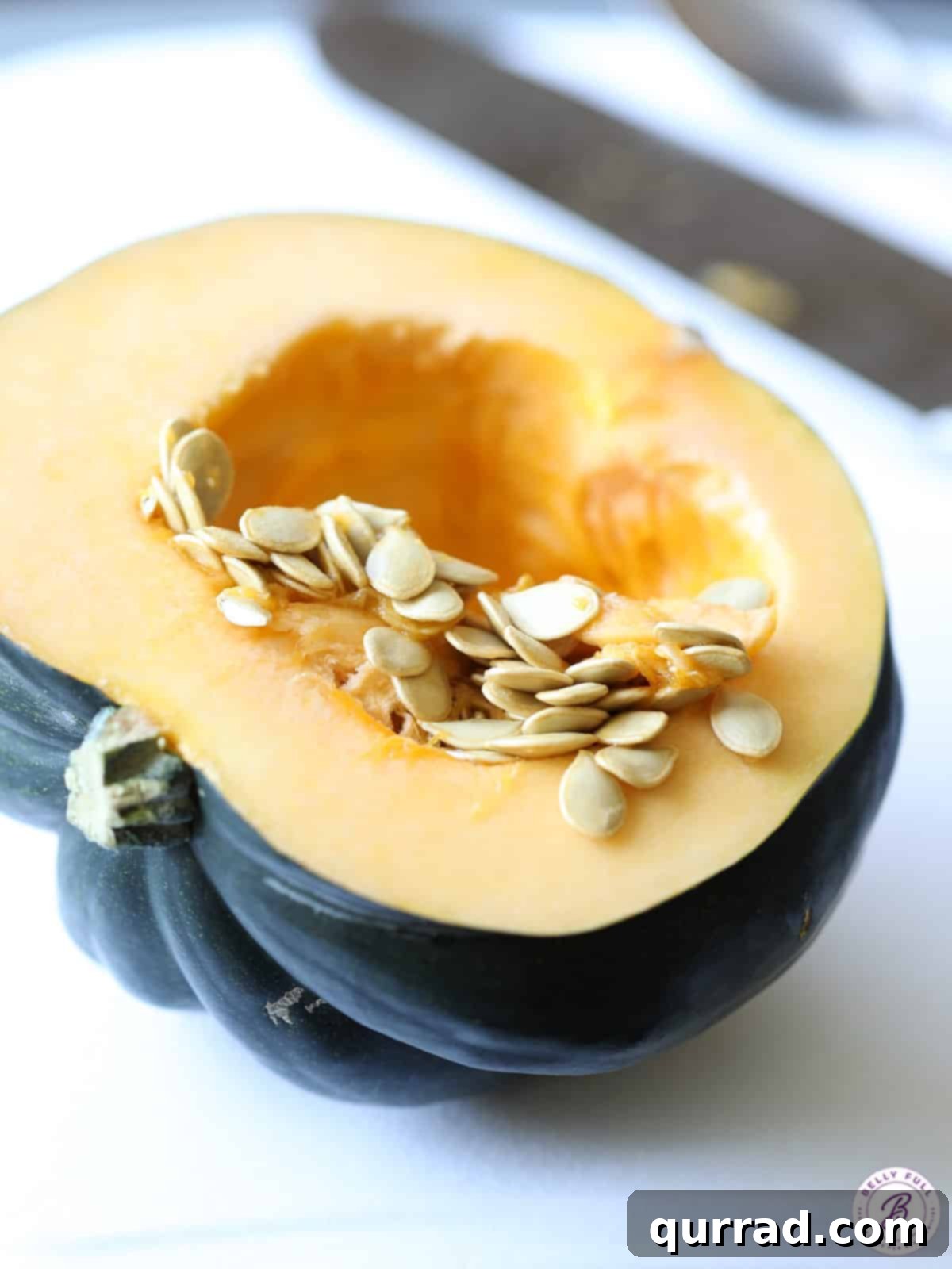 Raw acorn squash cut in half, revealing its vibrant interior and seeds, ready for preparation before roasting.