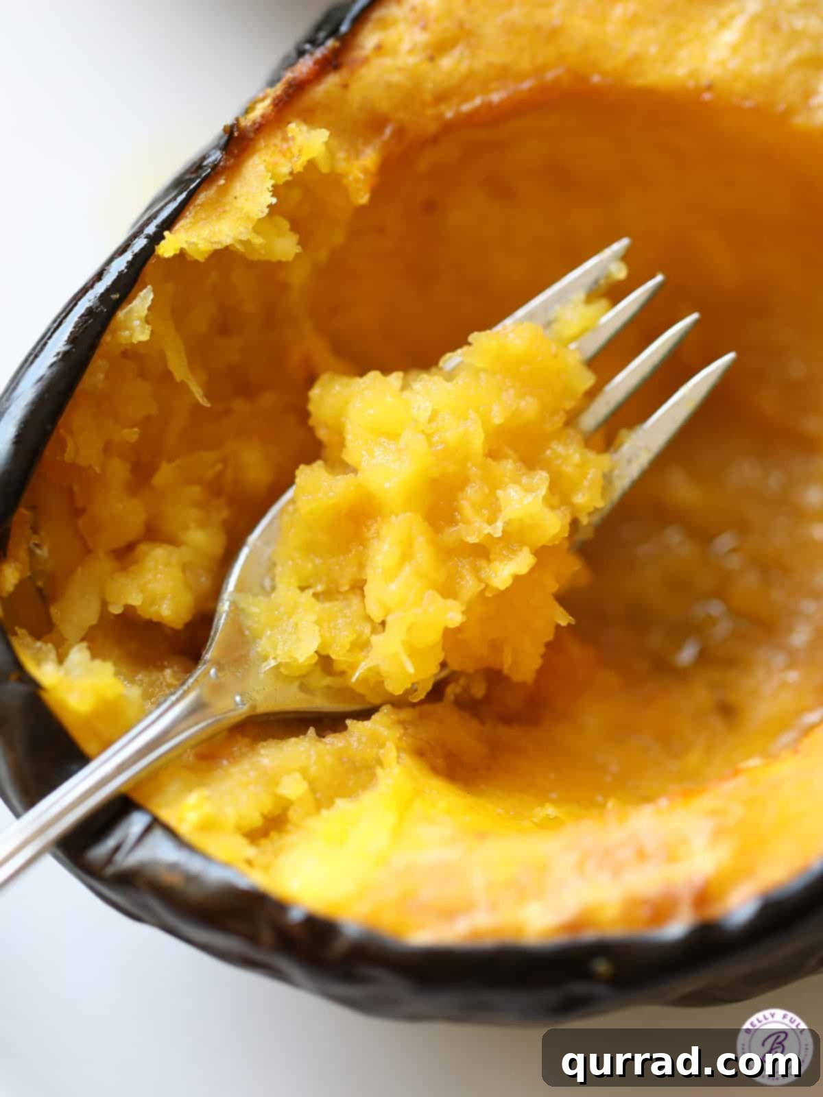 Close-up view of the tender, golden-orange flesh of a roasted acorn squash, being tested with a fork for perfect doneness.