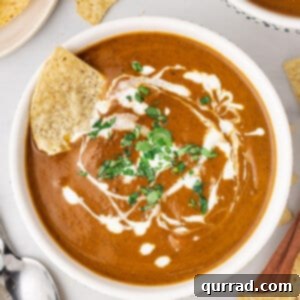 Small overhead bowl of black bean soup with cream and tortilla chip