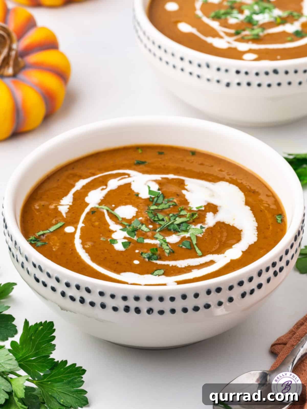 Golden Harvest Pumpkin Black Bean Delight 4 Close-up of a bowl of creamy pumpkin and black bean soup, artfully drizzled with a rich swirl of heavy cream, ready to be enjoyed.