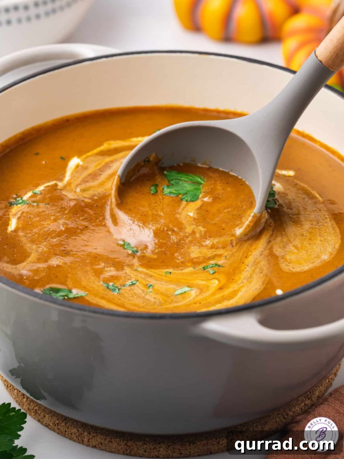 Golden Harvest Pumpkin Black Bean Delight 5 A large pot filled with smooth, golden-orange pumpkin and black bean soup, with a metal ladle resting inside, ready to serve.