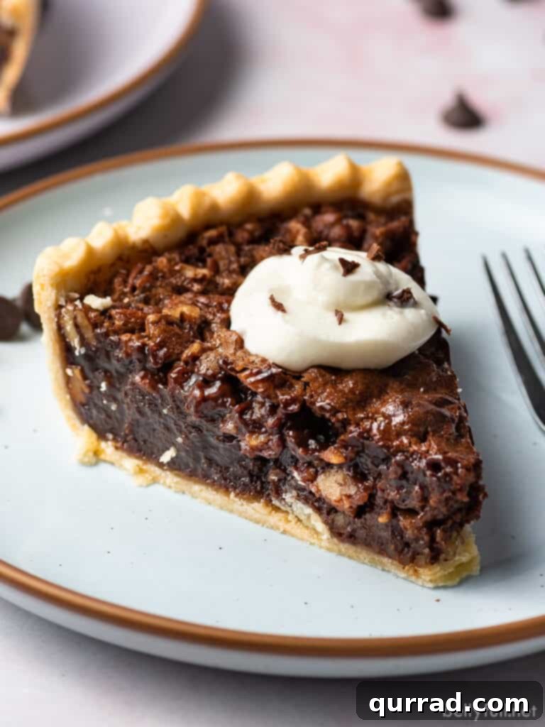 Close-up slice of rich Chocolate Pecan Pie, showcasing its gooey chocolate filling and whole pecans, ready to be enjoyed.