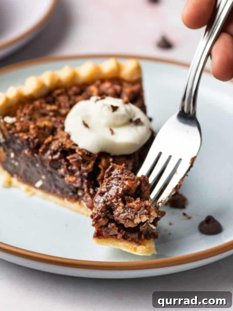 Close-up of a bite of Chocolate Pecan Pie on a fork, showing the rich chocolate filling and pecan pieces.