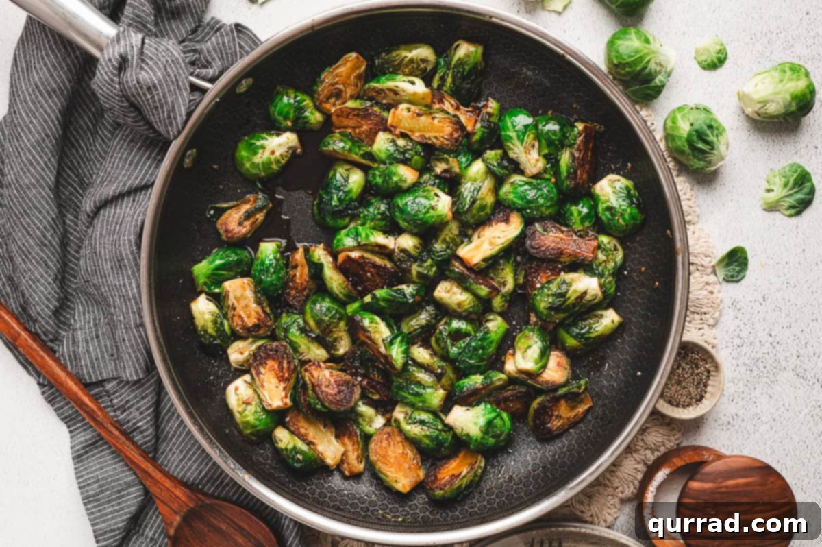 Caramelized Molasses Brussels Sprouts 8 Brussels sprouts in a skillet, coated in the molasses glaze, with a kitchen towel and wooden spoon beside the pan.
