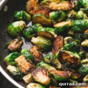 Close-up of sautéed Brussels sprouts in a skillet, golden brown on the cut sides and coated in a glossy molasses glaze.
