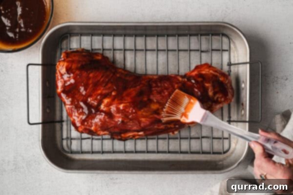 Glaze being brushed on top of uncooked tri tip steak, covering it evenly