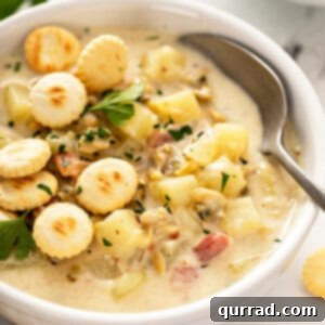 bowl of new england clam chowder with spoon topped with crackers