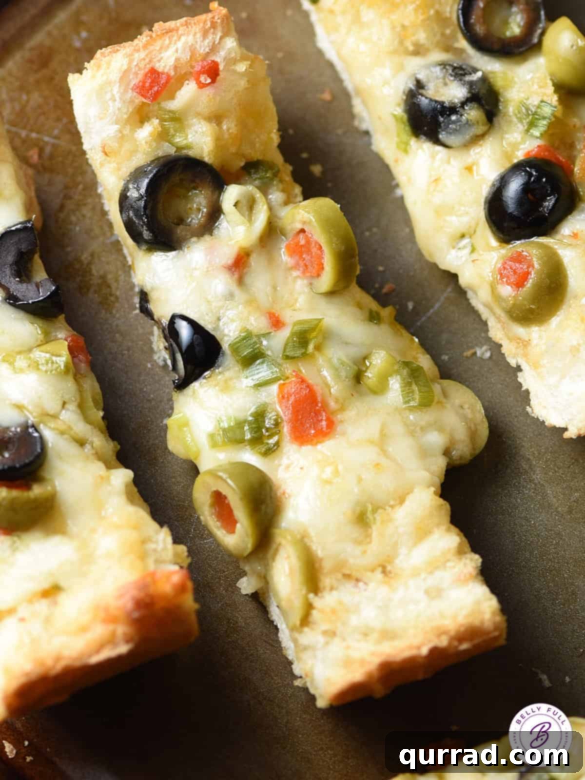 Mediterranean Olive & Cheese Artisan Loaf 4 overhead slice of gooey Olive Cheese Bread on baking sheet