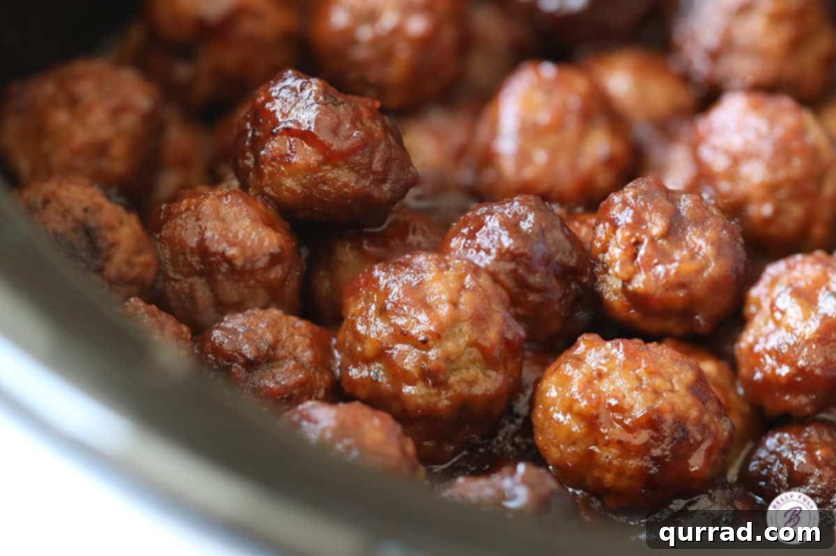 Crock-Pot Cranberry Glazed Meatballs 3 Cranberry meatballs simmering in a slow cooker, filling the pot with rich, glossy sauce.