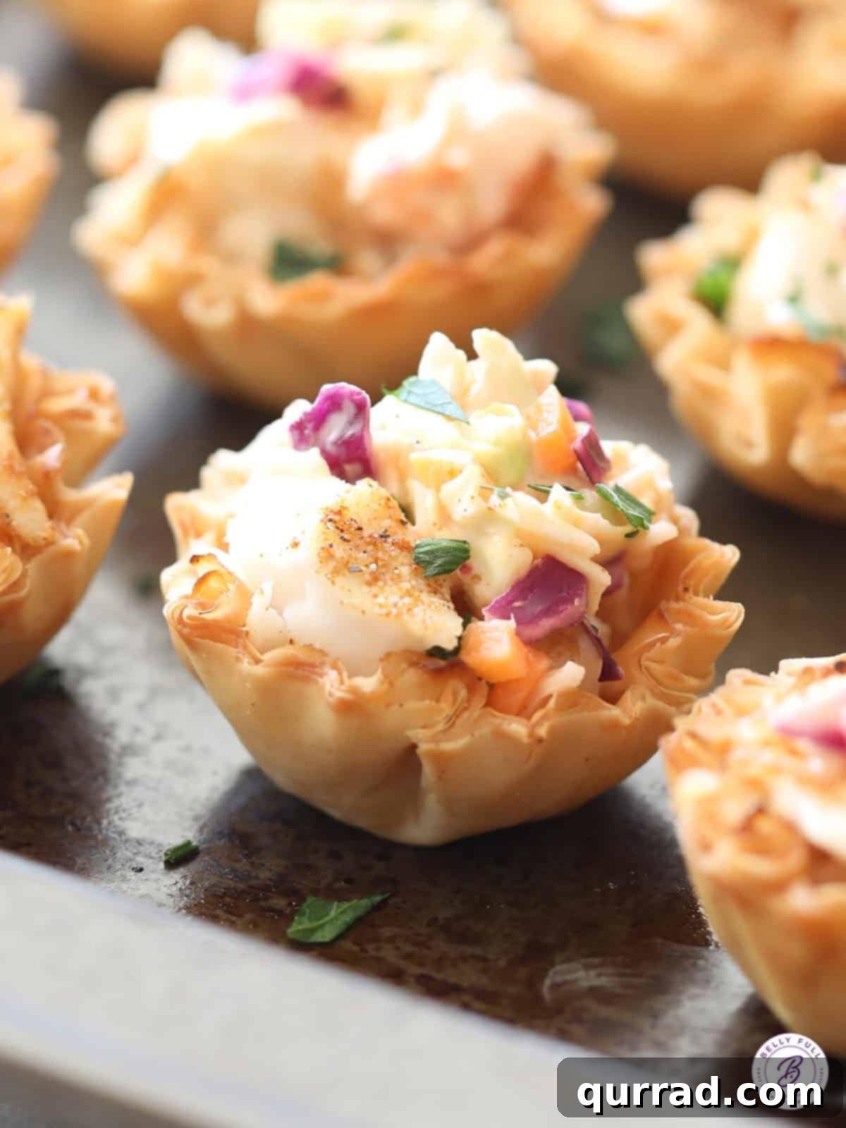 Crispy Mini Fish Tacos 2 Close up of Mini Fish Tacos in golden phyllo shells, topped with fresh slaw and a squeeze of lime.