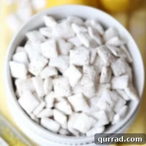 overhead picture of lemon muddy buddies in white bowl with whole lemons and zester on yellow napkin