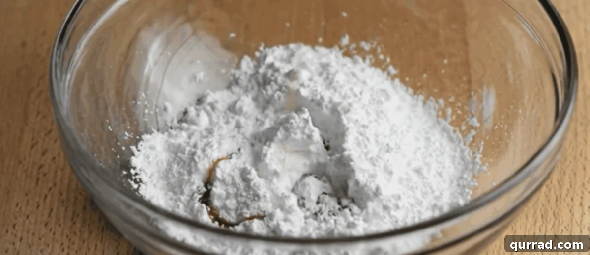 Effortless Mini Cinnamon Buns 7 Ingredients for the maple glaze, including maple syrup, milk, and powdered sugar, in a glass bowl.