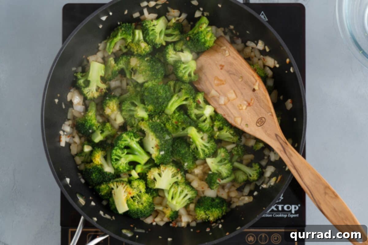 Savory Chicken and Broccoli Stir Fry 6 Sautéing onions and broccoli in a skillet with a wooden spoon, releasing vibrant colors.