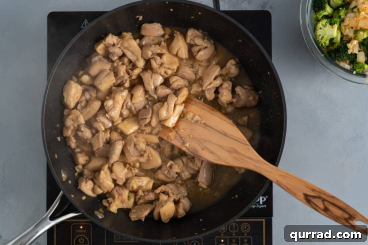 Savory Chicken and Broccoli Stir Fry 7 Cooking the chicken in a skillet with a wooden spoon, achieving a golden brown color.