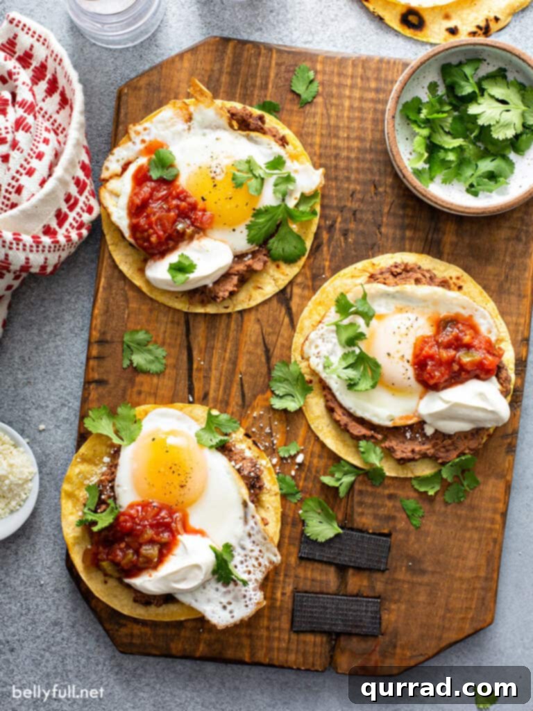Fiesta Morning Eggs 3 Overhead view of three corn tortillas with black beans and fried eggs on a wooden board