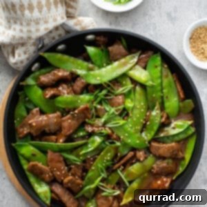 overhead beef stir fry with snow peas in skillet