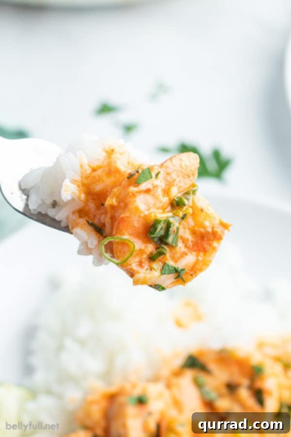 Creamy Thai Coconut Shrimp Curry 5 Close-up of cooked shrimp coated in creamy Thai curry sauce on a fork.
