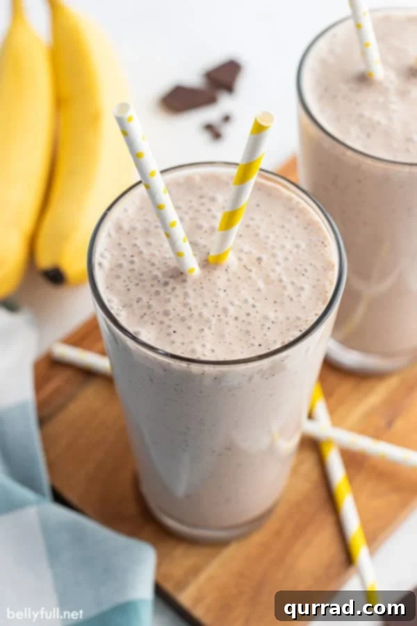 Morning Buzz Banana Blend 2 A tall glass of banana smoothie with a yellow and white striped straw, surrounded by fresh bananas.