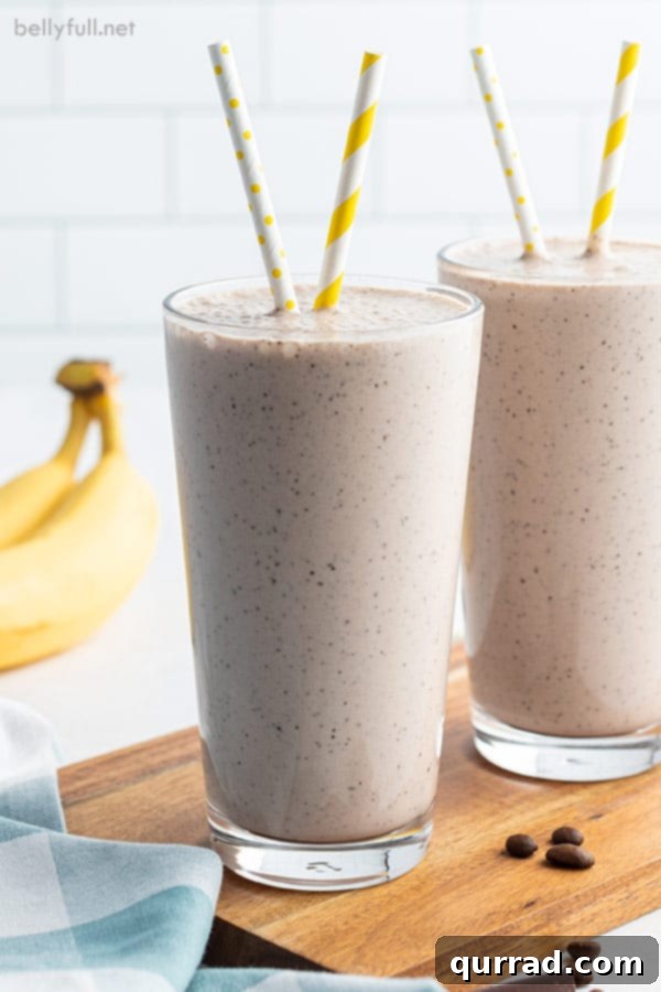 Morning Buzz Banana Blend 4 Two tall glasses filled with a vibrant banana smoothie, each adorned with a playful yellow striped straw.