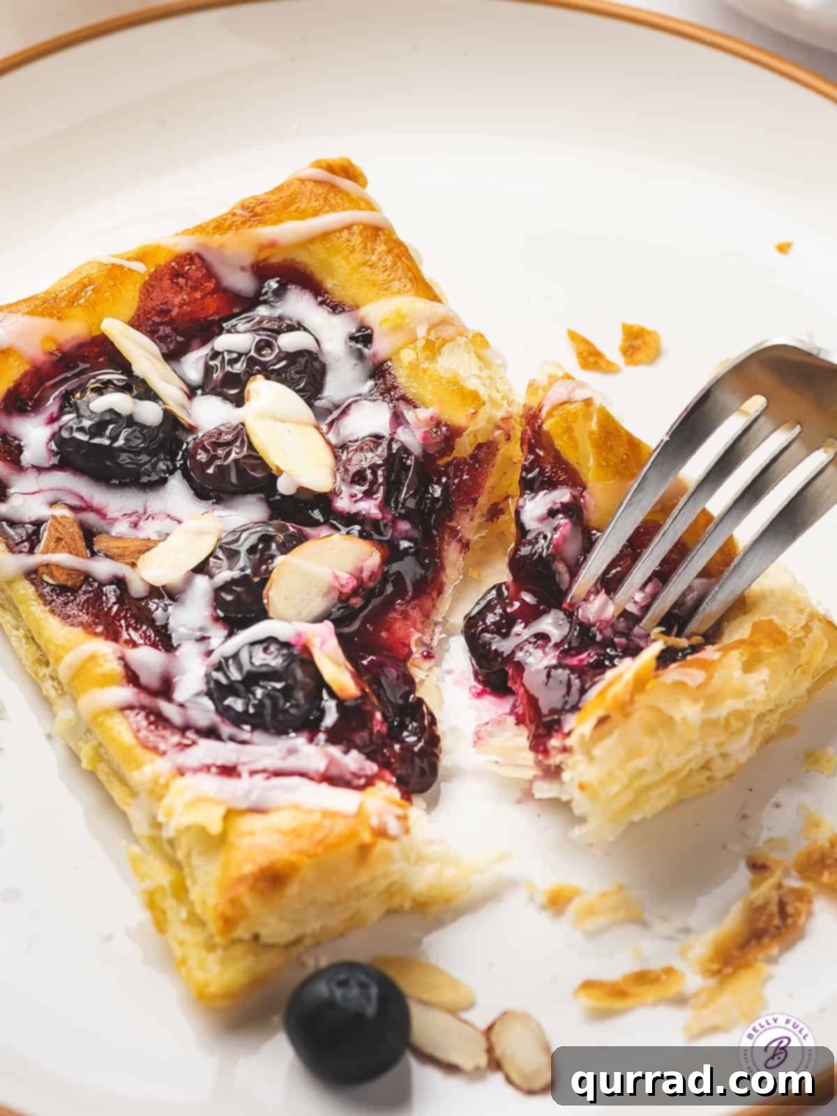 blueberry puff pastry tart with chunk removed on fork
