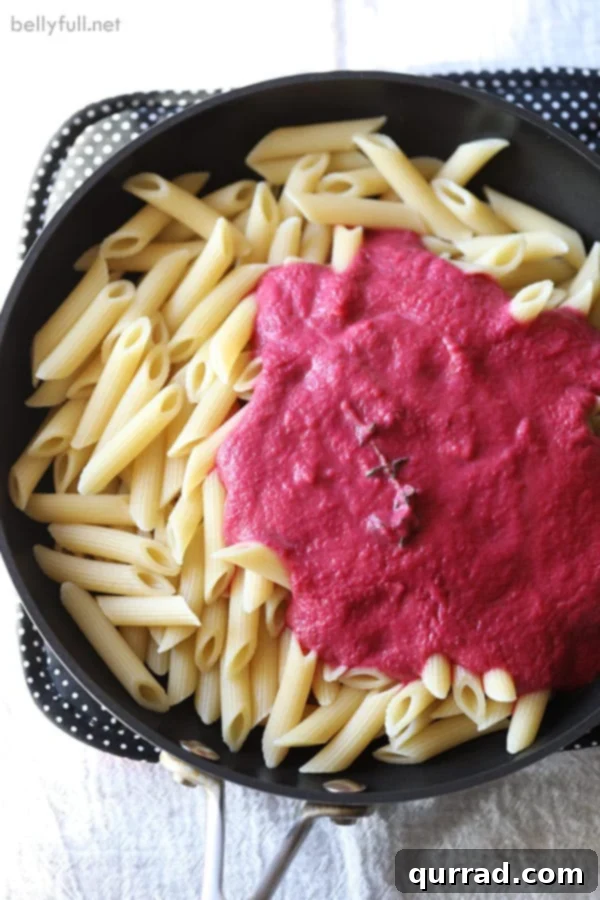 Velvet Beet Pasta 2 Penne pasta coated in a vibrant creamy beet sauce in a skillet, ready to be served.