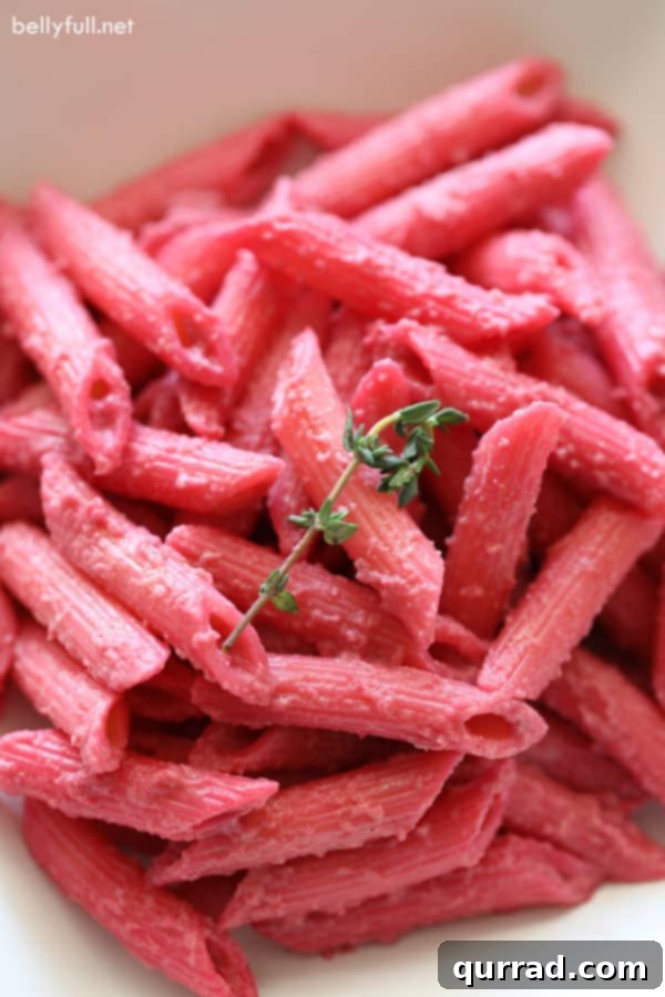 Velvet Beet Pasta 4 Serving of penne pasta with creamy beet sauce in a white bowl, garnished with fresh thyme, ready to eat.