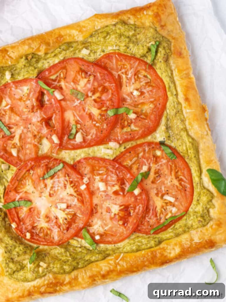 An overhead view of a beautifully baked tomato basil tart on parchment paper, showcasing its golden crust and vibrant tomato slices.