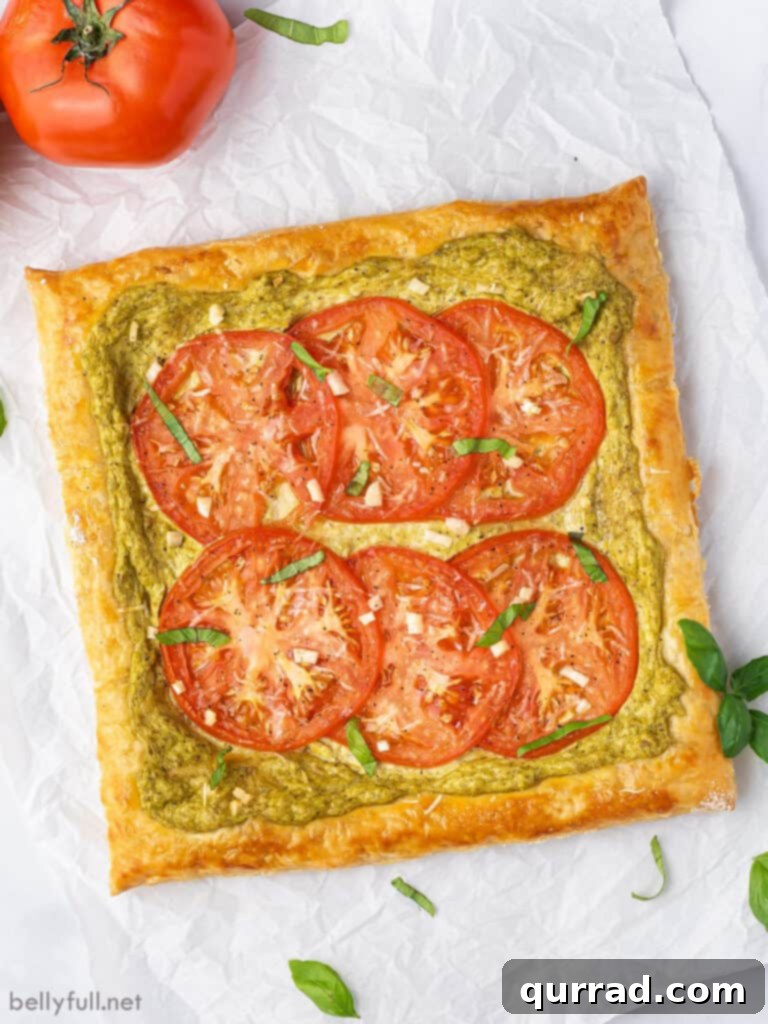 An overhead shot of a whole, golden-baked tomato tart on parchment paper, ready to be sliced and served.