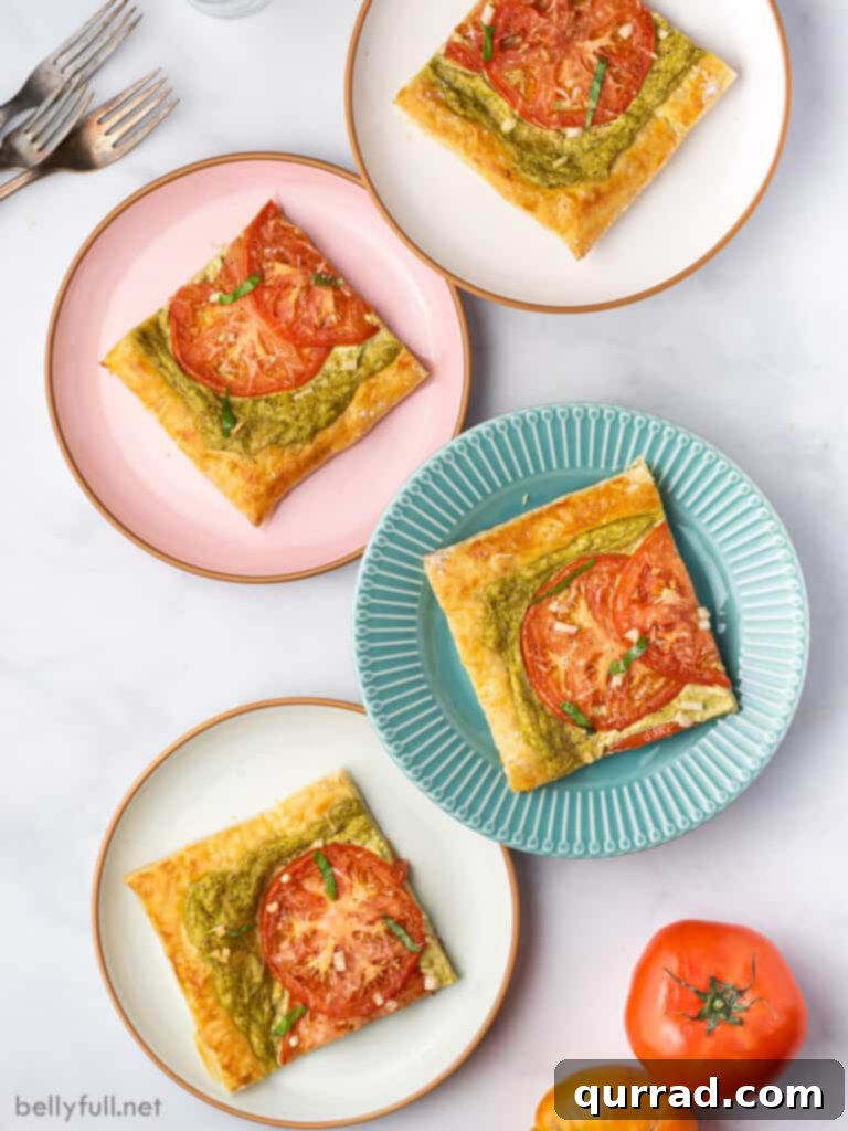 Four colorful plates, each holding a perfect slice of baked puff pastry tart with tomatoes and basil.
