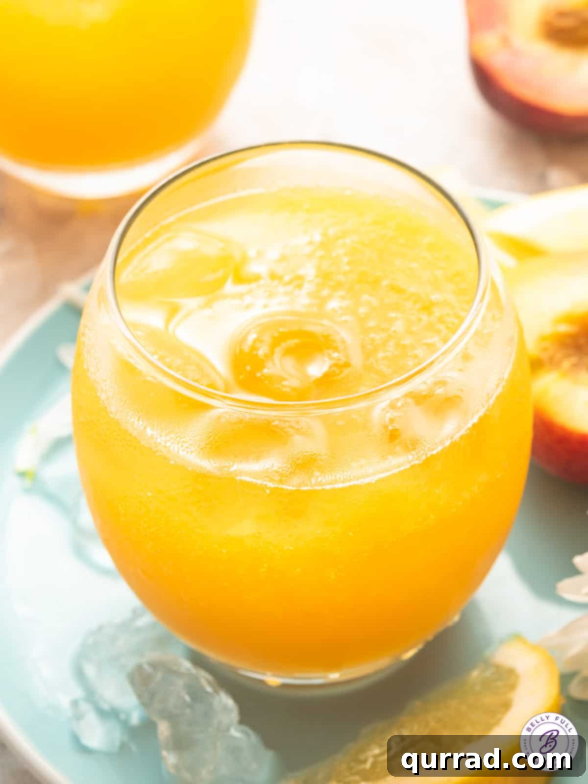 Glass of sparkling peach lemonade garnished with a peach slice and mint