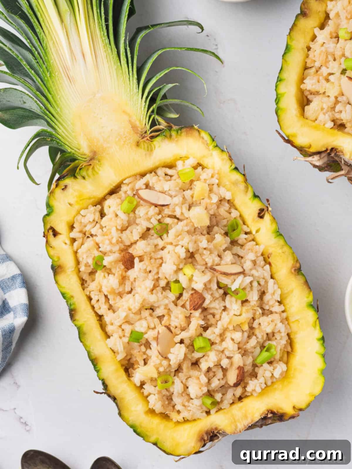 Tropical Coconut Pineapple Rice 2 Creamy pineapple coconut rice piled high inside a fresh, hollowed-out pineapple half, garnished with a spoon, ready to be served.