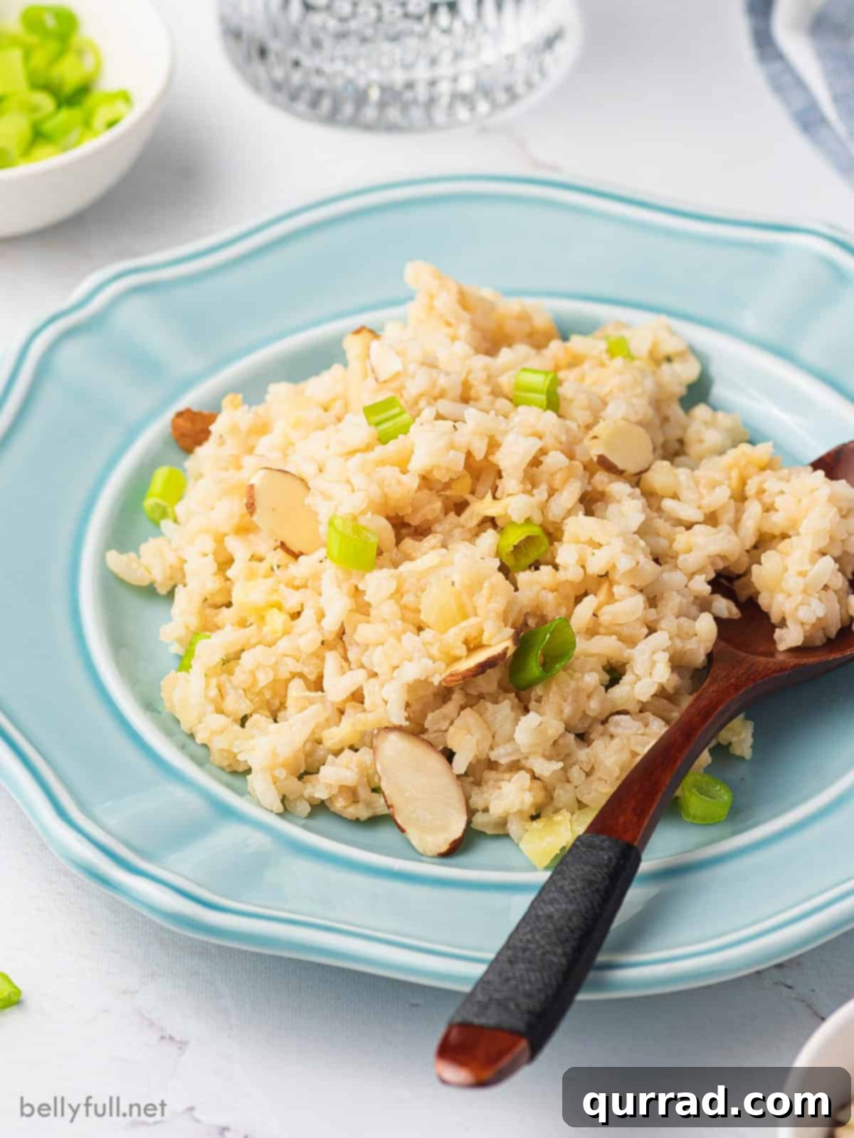 Tropical Coconut Pineapple Rice 6 A serving of pineapple coconut rice presented on a elegant blue plate with a spoon, highlighting its fluffy texture and tropical garnishes.