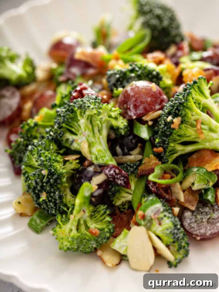 Sweet & Tangy Broccoli Crunch 4 A close-up of a serving of broccoli salad on a white plate, highlighting the detailed texture and deliciousness of each ingredient.