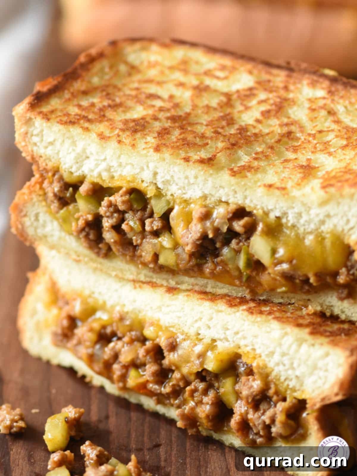 Tangy Dill Pickle Sloppy Joe Melt 4 A Dill Pickle Sloppy Joe Grilled Cheese sandwich, cut in half and stacked, revealing the layers of crispy bread, melted cheese, and flavorful sloppy joe filling.