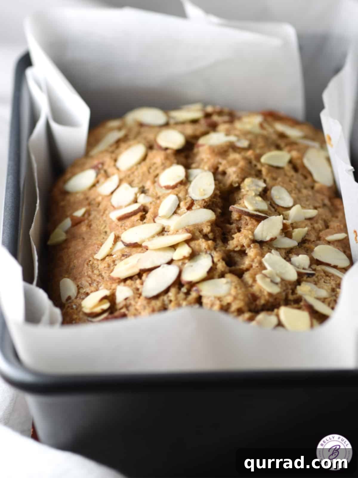 Creamy Almond Banana Bread 3 A whole loaf of freshly baked almond butter banana bread, garnished with perfectly toasted sliced almonds.