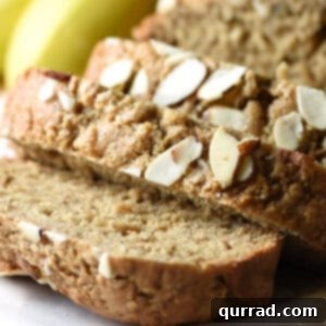 Creamy Almond Banana Bread 5 Close up of a moist slice of almond butter banana bread with almonds on top.