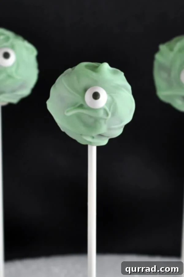 Halloween Cyclops Cake Pops 3 Close-up of a green one-eyed monster cake pop with a googly eye