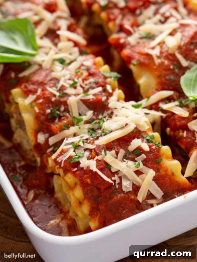 Close-up of golden brown sausage lasagna rolls baked in a casserole dish, bubbling with cheese and marinara sauce